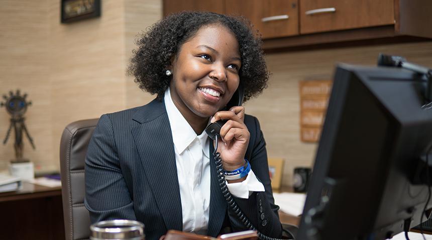 student at desk on the phone smiling